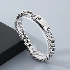 Macro detail of 12mm stainless steel Cuban chain bracelet with a smooth rectangular clasp