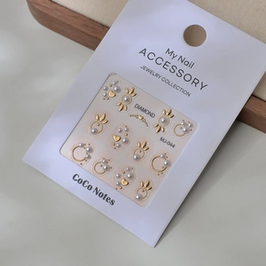 Set de stickers à ongles dorés avec perles et motifs cœurs sur support blanc élégant