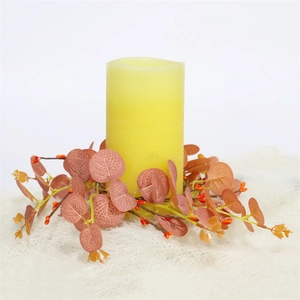 Detail of flameless candle with eucalyptus leaves and orange berries on plush white rug