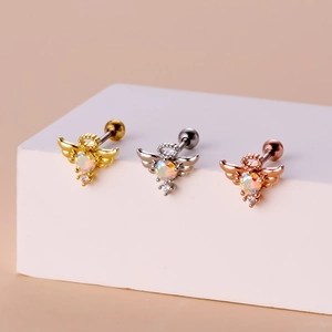 Macro view of three angel-shaped screw back earrings in gold, silver, and rose gold finish