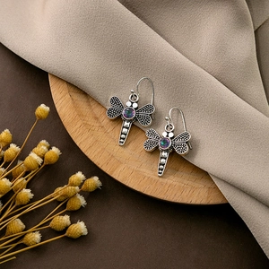 Detailed close-up of dragonfly drop earrings with antique silver finish and iridescent stone