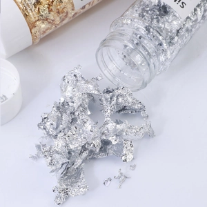 Macro detail of shining silver foil flakes spilling from a clear bottle for DIY crafts