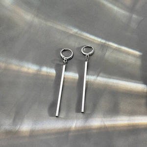 Detail of silver long bar geometric drop earrings on gray textured fabric background