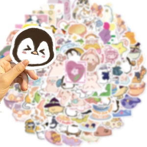 Close-up of hand holding a cute penguin sticker from a waterproof cartoon decal set