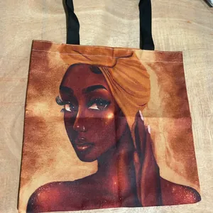 Reusable canvas tote bag featuring an artistic African woman portrait on a wooden surface