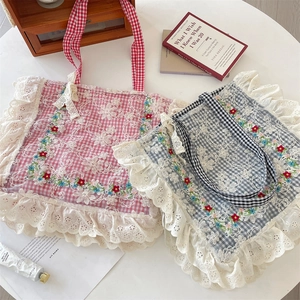 Detail of floral embroidery and lace trim on pink and black checkered tote bags