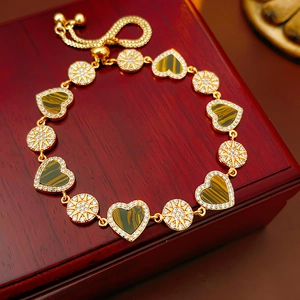 Detail of 18K gold plated heart bracelet with tiger eye stones on wooden jewelry box