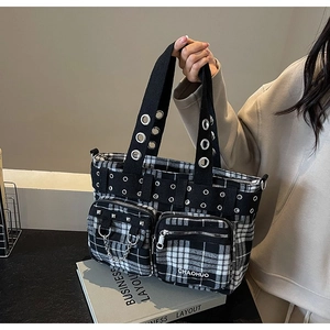 Close-up of black and white checkered punk tote bag with metal eyelets and chains