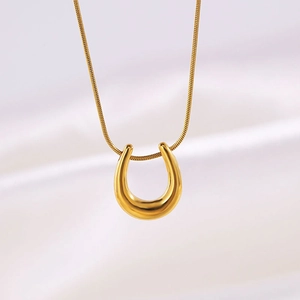 Close-up of a 18k gold-plated U-shaped pendant on a fine snake chain over white silk
