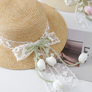 Flat top straw sun hat with white lace trim and green tulip ribbon bow for summer