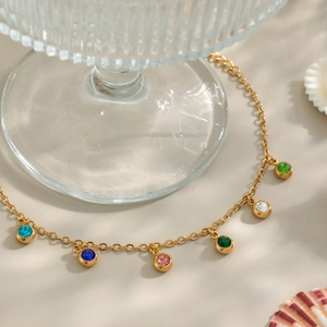 Detail of 18K gold-plated chain with multi-color zircon charms on glass base