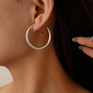Close-up of minimalist silver hoop earrings on model with high gloss metallic finish