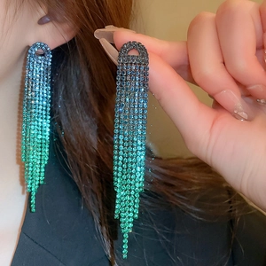Close-up of dangling rhinestone tassel earrings with blue and green gradient crystals