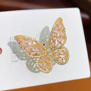 Macro detail of gold plated butterfly ring featuring pink and white sparkling crystals