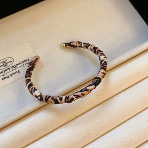 Detail of leopard print twisted cuff bracelet with gold metal end beads on soft lining
