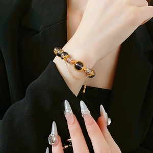 Detailed close-up of vintage beaded bracelet with bronze glass beads on black suit background