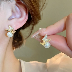 Elegant gold butterfly earrings with zircon inlay and pearls shown in a close-up wear