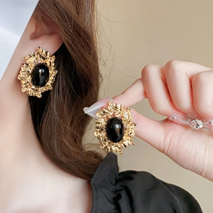 Detail von Vintage-Ohrringen in Goldoptik mit schwarzem Edelstein und Blattrelief