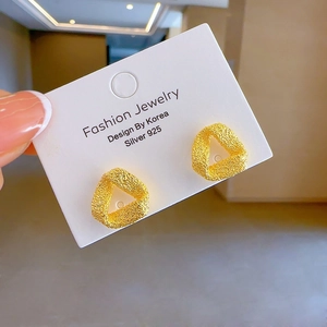 Close-up of matte gold triangular stud earrings with S925 silver posts on a card