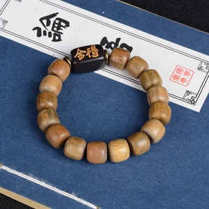Détail macro du bracelet en bois de santal avec calligraphie Shede sur perle noire
