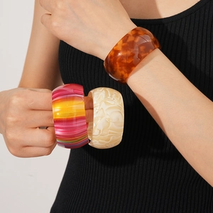 Detail of wide resin bracelets in tortoiseshell, striped, and marble patterns on wrist