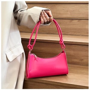 Detail of a glossy magenta baguette bag showing polished texture and elegant knot strap