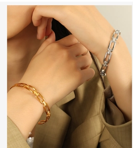 Close-up of gold and silver chain link bracelets worn by a model in a trendy style