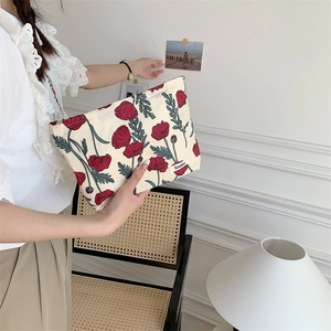 Close-up of floral cotton pouch with red poppy pattern and a small brand label