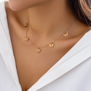 Close-up of double-layer gold necklace with butterfly pendants and rhinestone accents