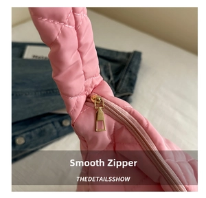 Close-up of golden zipper detail on pink quilted shoulder bag with rhombus stitching