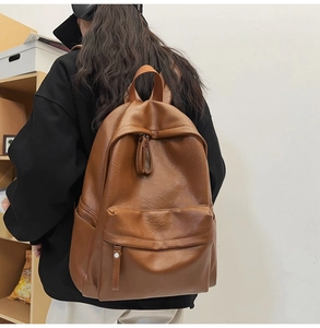 Side view of caramel brown soft leather backpack with front zipper pocket on model