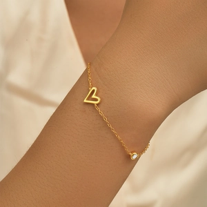 Close-up of gold S925 silver heart bracelet with sparkling round diamond on wrist