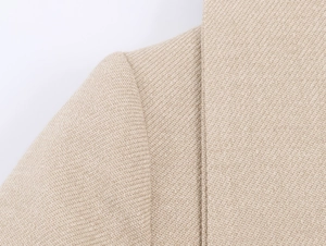 Macro shot of beige herringbone twill fabric texture and stitching on suit jacket shoulder