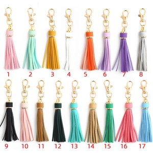 Set of 17 colorful faux leather tassel keychains with golden lobster clasps on white background