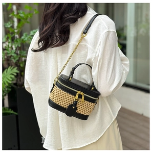 Rear view of a woven leather shoulder bag with chain strap and top handle on a model