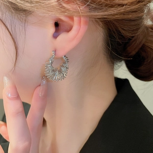 Silver geometric spiral C-shaped hoop earrings with multi-layered metallic texture on model