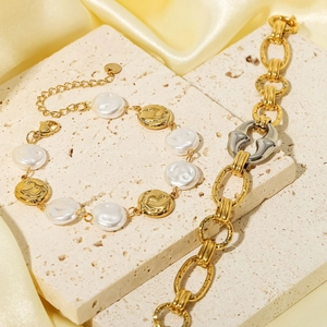 Layered gold and silver oval chain bracelet with pearl accents on travertine stone base