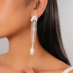 Detailed view of silver fishbone drop earring with zircon and white pearl on model