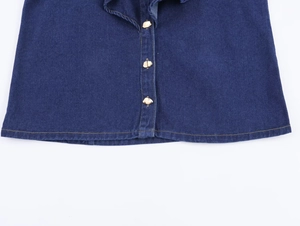 Détail d'une chemise en jean bleu foncé avec boutons dorés et surpiqûres jaunes