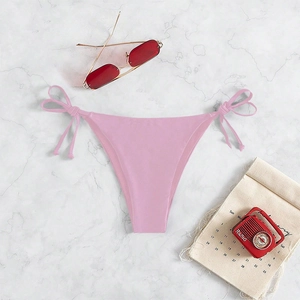 Flat lay of pink tie-side bikini bottom on marble background with retro summer props