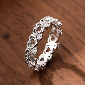 Close-up of silver hollow heart ring featuring sparkling zircon stones on wood surface