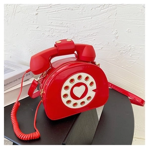 Macro detail of red vintage telephone shaped handbag with retro rotary dial and handset
