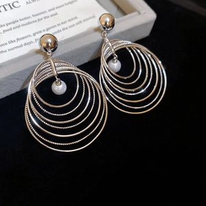 Macro shot of multi-layered silver circular earrings with pearl pendants on black velvet