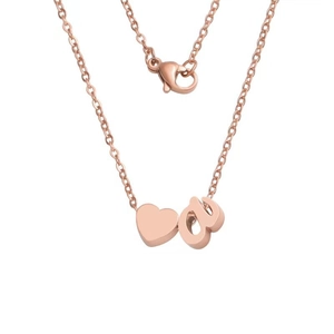 Detail of rose gold necklace with polished heart and lowercase letter 'a' pendant