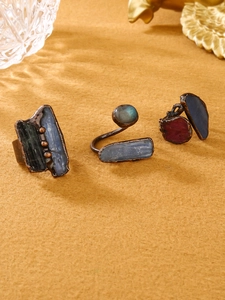 Close-up of three vintage raw stones rings with kyanite and labradorite on felt surface