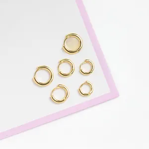 Detailed shot of three sets of polished 18K gold-plated minimalist hoop earrings in varied sizes