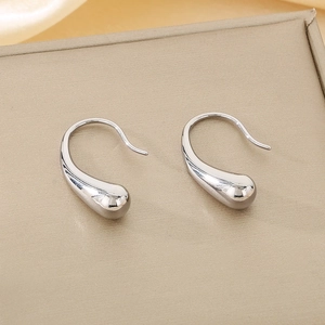 Macro shot of silver teardrop earrings with a polished mirror finish on leather