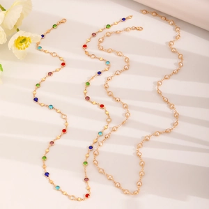 Detailed view of long gold station necklaces with colorful gemstones and white pearls