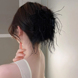 Detail shot of elegant black ostrich feather hair claw clip on a low bun hairstyle
