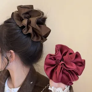 Macro detail of glossy satin scrunchies with elegant ruffles in dark coffee and wine red